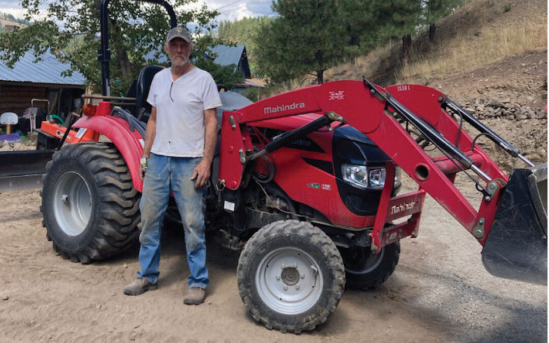 Clifford Calhoon standing in front of a red backhoe